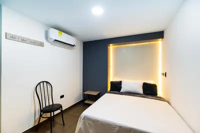 a small bedroom with a bed and a chair at Hotel LAX78 in Medellín