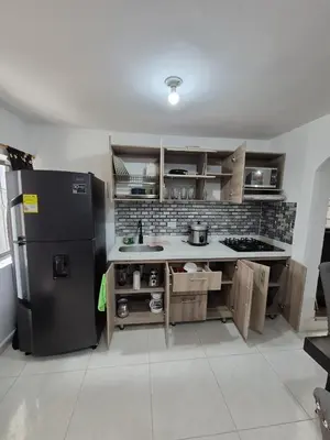 a kitchen with a black refrigerator and wooden cabinets at BONITO y ELEGANTE APARTAMENTO in Medellín