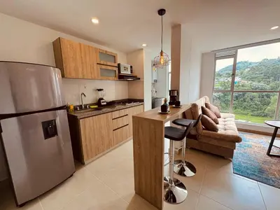 a kitchen with a stainless steel refrigerator and a couch at Espectacular vista, apto de lujo, piscina, gym in Manizales