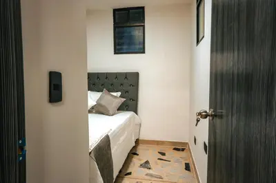 a bedroom with a bed with a black headboard and a door at Apartamento Rosales in Medellín