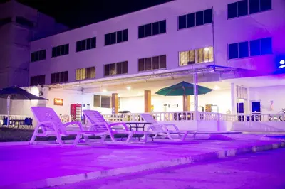 a group of purple chairs and an umbrella in front of a building at Hotel Mall Santana Del Río in La Dorada