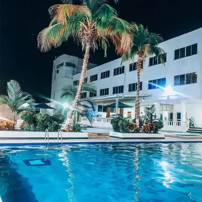 a swimming pool with palm trees in front of a building at Hotel Mall Santana Del Río in La Dorada