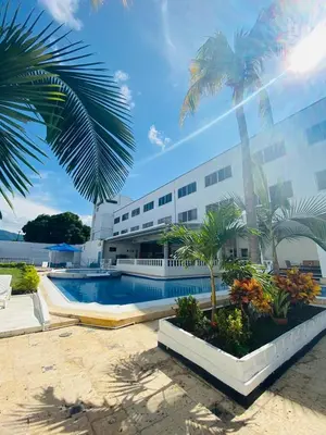 a building with a swimming pool and palm trees at Hotel Mall Santana Del Río in La Dorada