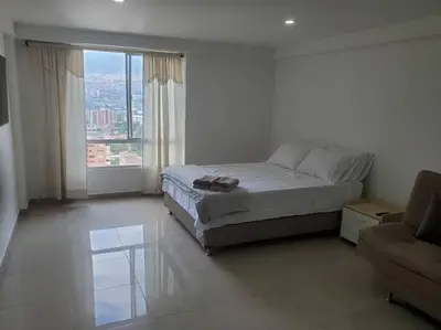 a white bedroom with a bed and a couch at Mde Escape in Medellín