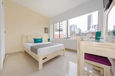 a bedroom with a bed and a large window at Hotel Ana Carolina in Manizales