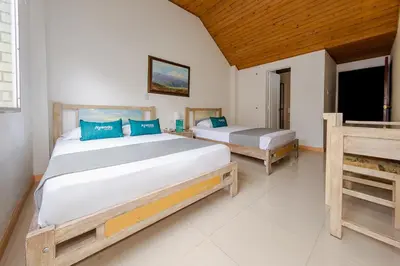 a bedroom with two beds with blue pillows at Hotel Ana Carolina in Manizales