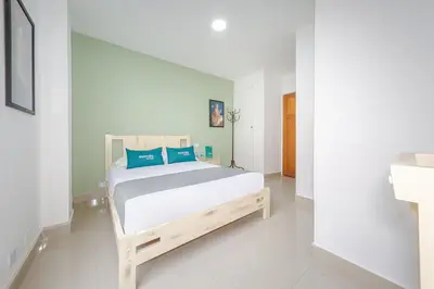 a bedroom with a large bed with blue pillows at Hotel Ana Carolina in Manizales