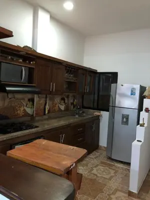 a kitchen with wooden cabinets and a white refrigerator at Casa santorini in Puerto Triunfo
