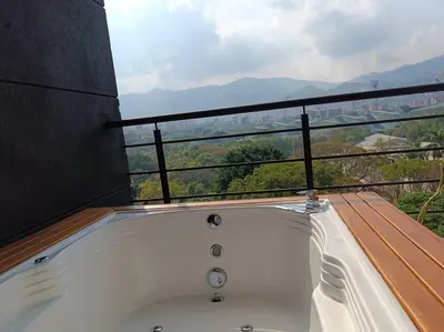 a bath tub on a balcony with a view at Penthouse Estadio Medellín in Medellín