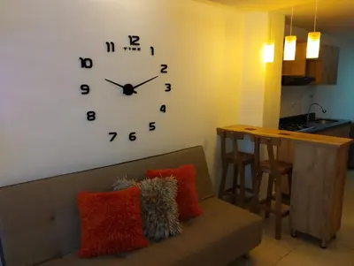 a large clock on a wall above a couch at Hermoso aparta estudio en Medellin in Medellín