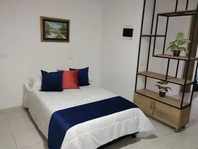 a bedroom with a bed with blue and red pillows at Hermoso aparta estudio en Medellin in Medellín