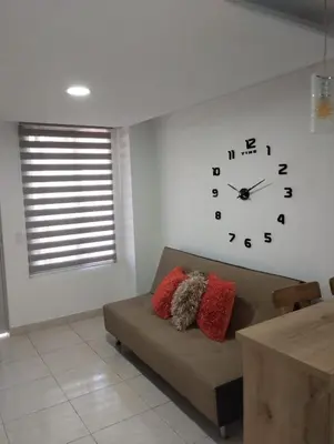 a living room with a couch and a clock on the wall at Hermoso aparta estudio en Medellin in Medellín