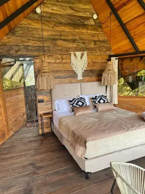 a bedroom with a large bed in a wooden cabin at Ecoedén glamping in Guatapé