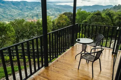 a table and two chairs on a balcony with a view at Refined cabin, panoramic views, steps from Jericó in Jericó