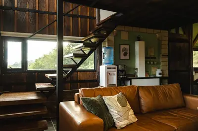 a living room with a brown couch and a staircase at Refined cabin, panoramic views, steps from Jericó in Jericó