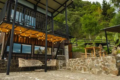 a house with a balcony with a table and chairs at Refined cabin, panoramic views, steps from Jericó in Jericó