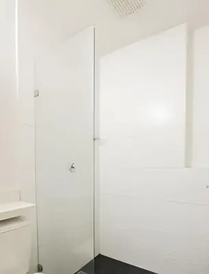 a glass shower door in a white bathroom at ApartaSuite moderno. Gran Vista. in Medellín