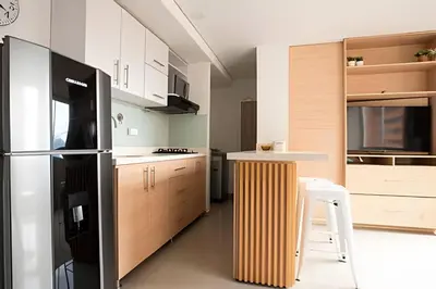 a kitchen with a refrigerator and a table in it at ApartaSuite moderno. Gran Vista. in Medellín