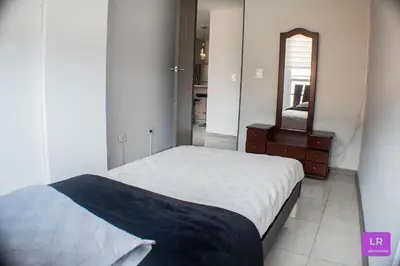 a bedroom with a bed and a dresser and a mirror at Apartamento Lujoso y Nuevo en Milán in Manizales