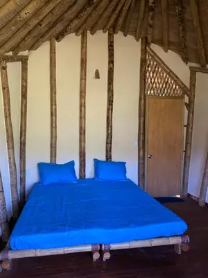 a bed with blue pillows and a wooden ceiling at Macuá, Refugio del bosque in San Rafael
