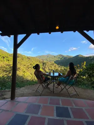 two women sitting at a table with a view of mountains at Macuá, Refugio del bosque in San Rafael