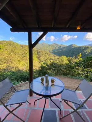 a table and chairs on a patio with mountains in the background at Macuá, Refugio del bosque in San Rafael