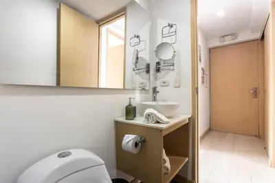 a bathroom with a toilet and a sink and a mirror at San Peter Aparta Suite en La 70 Laureles in Medellín