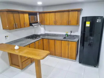 a kitchen with wooden cabinets and a black refrigerator at Cómodo apartament tipo loft en El Peñol in El Peñol