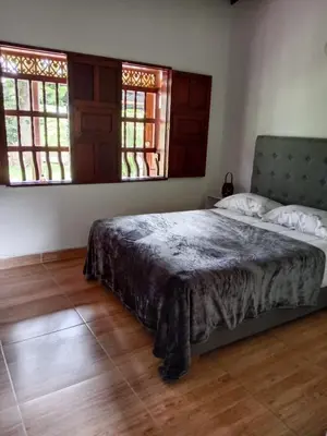 a bedroom with a bed and two windows at Hermosa Villa La Laja Rionegro in Rionegro