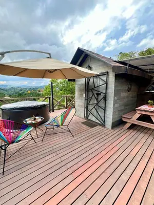 a deck with a table and chairs and an umbrella at Eco Lodge Glamping in Guatapé