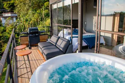 a jacuzzi tub on a balcony with a bed at Eco Lodge Glamping in Guatapé