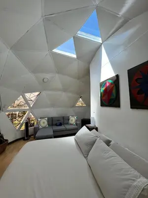 a bedroom with a large white bed and a couch at Eco Lodge Glamping in Guatapé