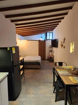 a kitchen with a refrigerator and a table and a bed at Apartaestudio en El Poblado in Medellín