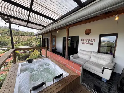 a hot tub on a deck with a couch at EDYMA Cabaña con JACUZZI in Guatapé