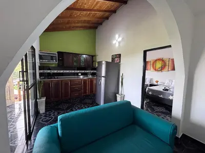 a living room with a blue couch and a kitchen at EDYMA Cabaña con JACUZZI in Guatapé
