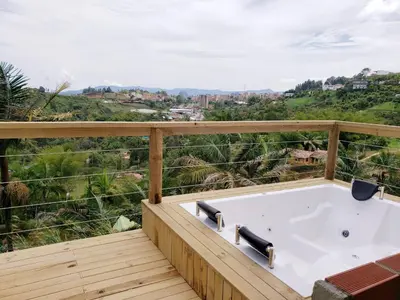 a hot tub on a wooden deck with a view at EDYMA Cabaña con JACUZZI in Guatapé