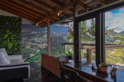 a room with a table and a view of the mountains at EDYMA Cabaña con JACUZZI in Guatapé
