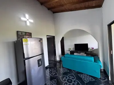 a living room with a blue couch and a refrigerator at EDYMA Cabaña con JACUZZI in Guatapé
