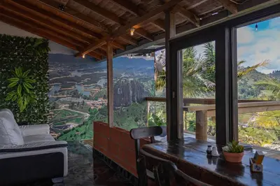 a room with a table and a view of the mountains at EDYMA Cabaña con JACUZZI in Guatapé