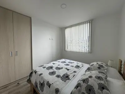 a white bedroom with a bed and a window at Barcelona in Manizales