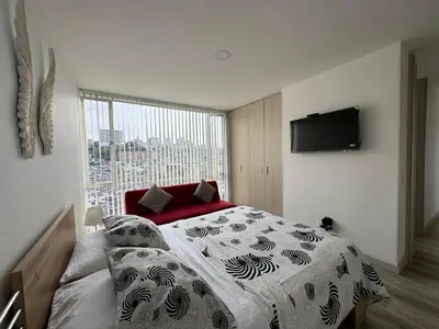 a bedroom with a large bed and a large window at Barcelona in Manizales