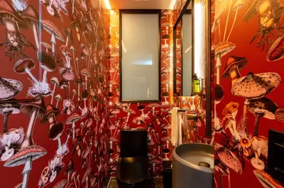 a bathroom with a red wall with shoes on it at Primavera Luxury Apartments Medellin in Medellín