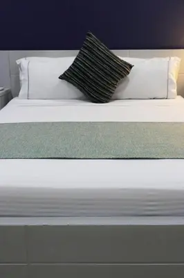 a white bed with two pillows on top of it at Hotel Lleras 10 in Medellín
