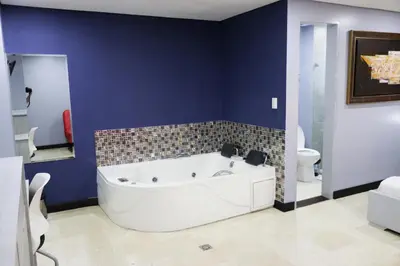 a bathroom with a white tub and a blue wall at Hotel Lleras 10 in Medellín