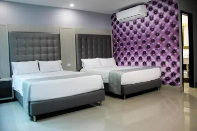a bedroom with two beds and a purple wall at Hotel Lleras Express in Medellín