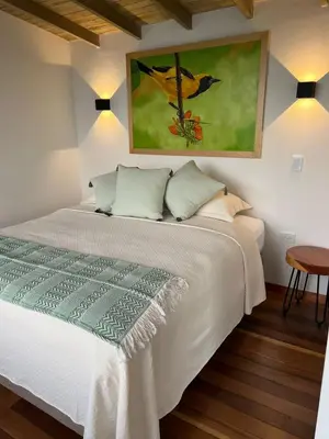 a bedroom with a white bed with a painting on the wall at Hotel Monteverde Campestre in Concordia