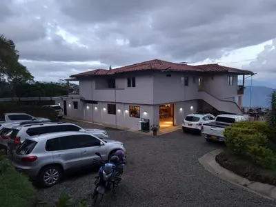 a large house with cars parked in a parking lot at Hotel Monteverde Campestre in Concordia