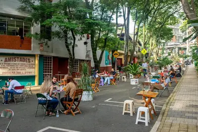 a group of people sitting at tables on a street at Comoda habitacion baño compartido en el Poblado-A4 in Medellín