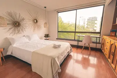 a bedroom with a bed and a large window at Bello alojamiento baño compartido en el Poblado-A5 in Medellín