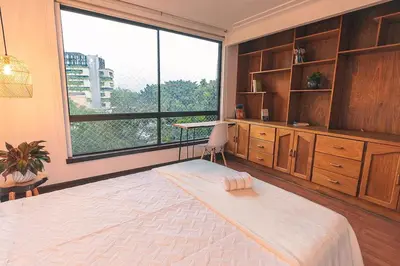 a bedroom with a large bed and a large window at Bello alojamiento baño compartido en el Poblado-A5 in Medellín